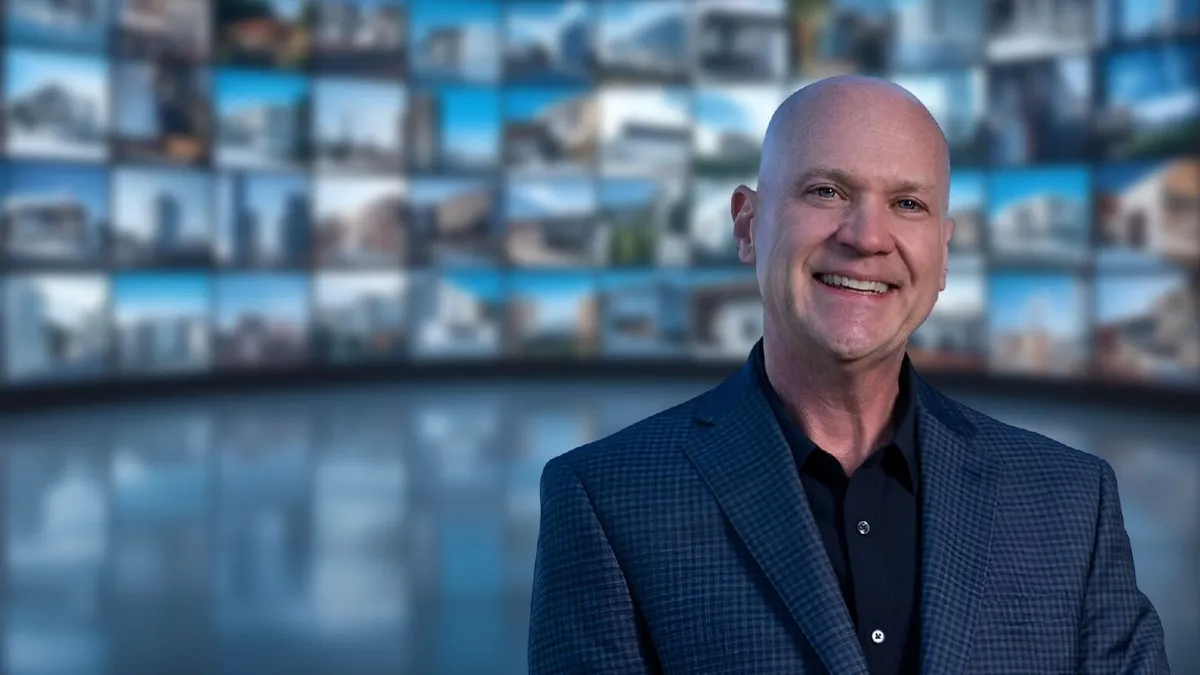 Jody McNamer, real estate coach, before a wall of screens
